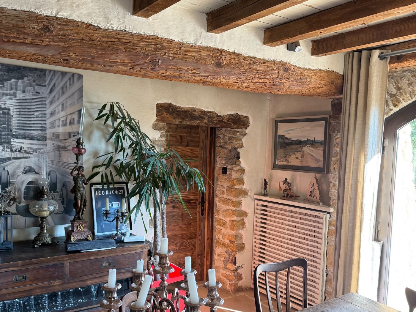 Salle à manger sous poutres encombrée après travaux, poussière sur le mobilier et le sol