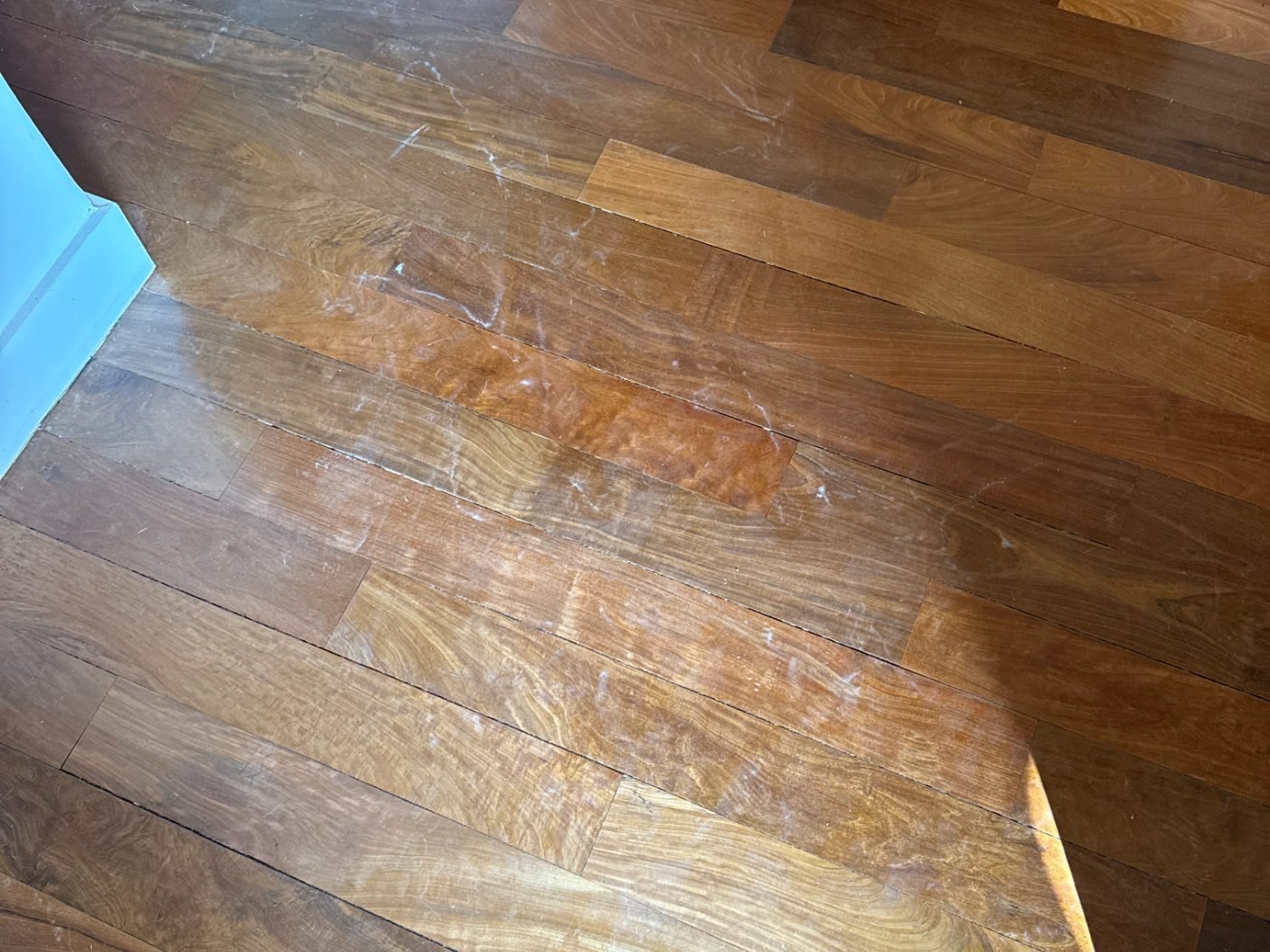Parquet ancien couvert de poussière de ponçage et de traces de chantier avant nettoyage