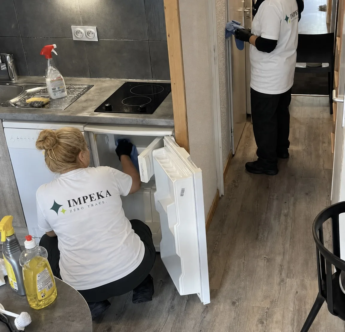 Deux agents Impeka nettoient la cuisine et le réfrigérateur d'un appartement