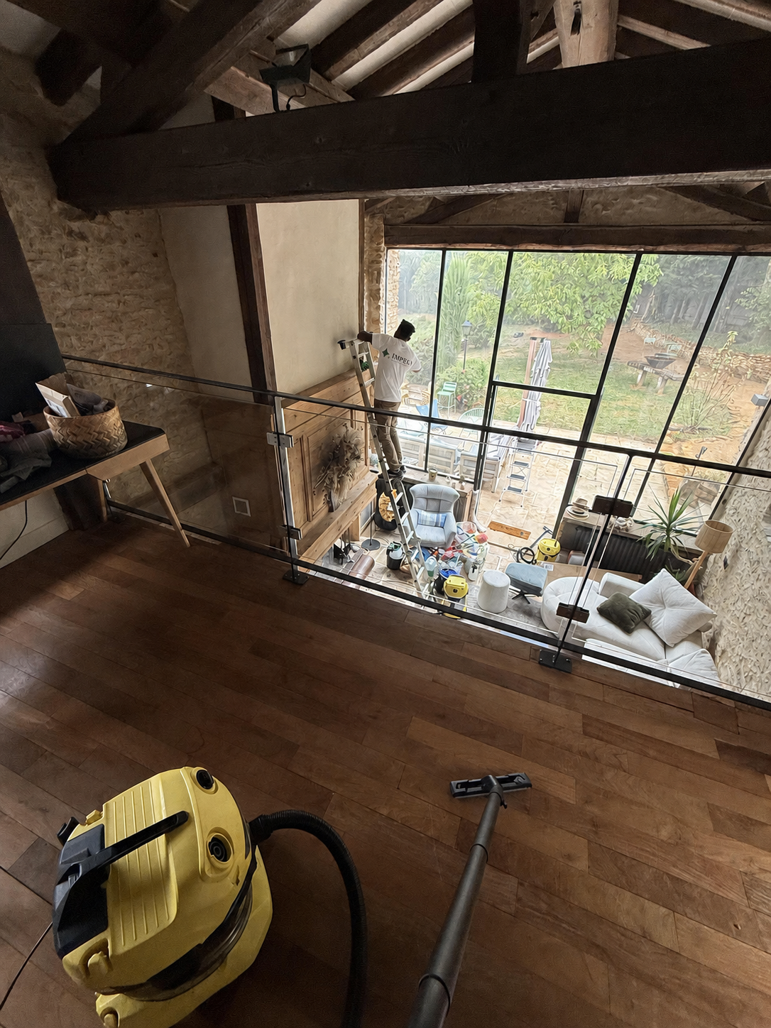 Agent IMPEKA en polo nettoie la verrière d'une maison en Île-de-France, aspirateur eau au premier plan