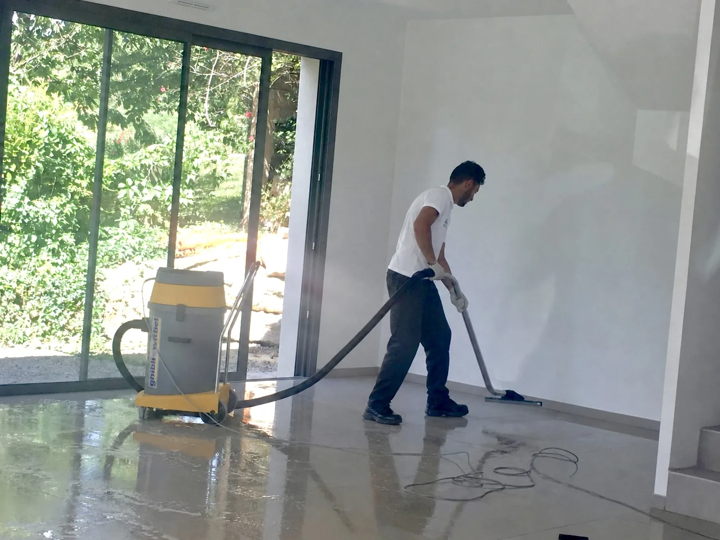 Agent Impeka aspire l'eau de lavage du sol d'une maison à l'aspirateur professionnel